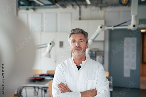 Smiling mature scientist standing with arms crossed in laboratory photo