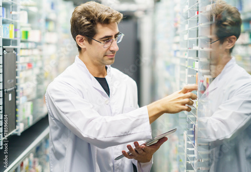 Pharmacist examining medicine stock on shelves at pharmacy photo