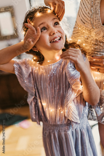 Wallpaper Mural Mother adjusting string light on daughter's forehead at home Torontodigital.ca