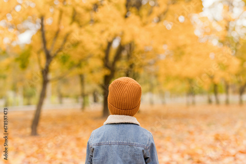 Boy wearing denim jacket and yellow knit hat at autumn park photo