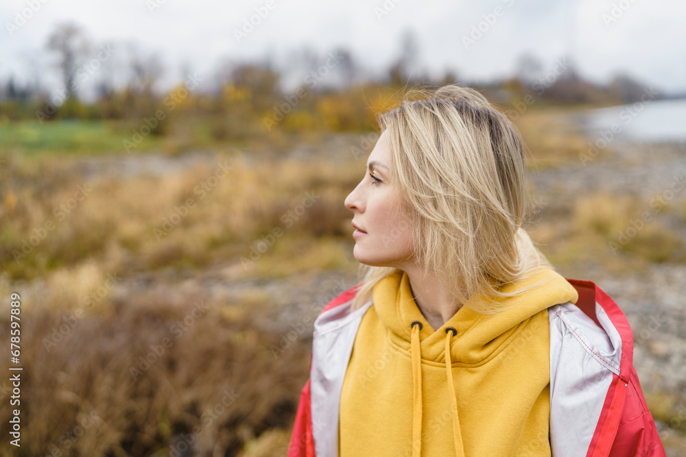 Thoughtful blond woman wearing hooded shirt in autumn park Thoughtful blond woman wearing hooded shirt in autumn park