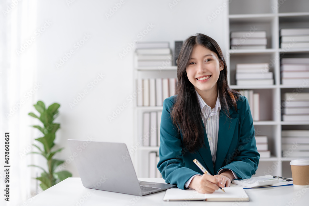 Financier working with documents at workplace. Young Asian business woman sitting working in modern office with documents and laptop computer. Financier working with documents at workplace. Young Asian business woman sitting working in modern office with documents and laptop computer.