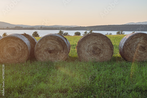 A golden field of hay bales, a serene lake at a sunset.