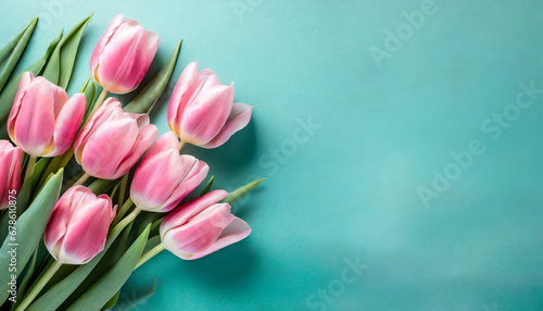 Pink tulips on turquoise background with copy space. Top view photo