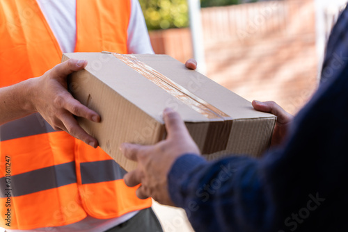 Delivery man delivering a package to the customer. Close-up of hands and cardboard box.