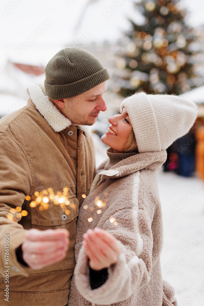 Happy romantic couple posing with bengal lights outdoors in winter
