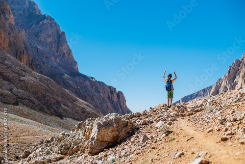 little boy with a backpack stands along the path against the backdrop of the mountains. travel with children to the mountains. Turkey. Aladaglar.