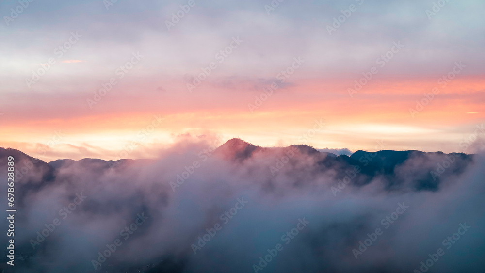 Landscape image of the sunrise in the morning with beautiful purple light on the mountains and hidden by fog.