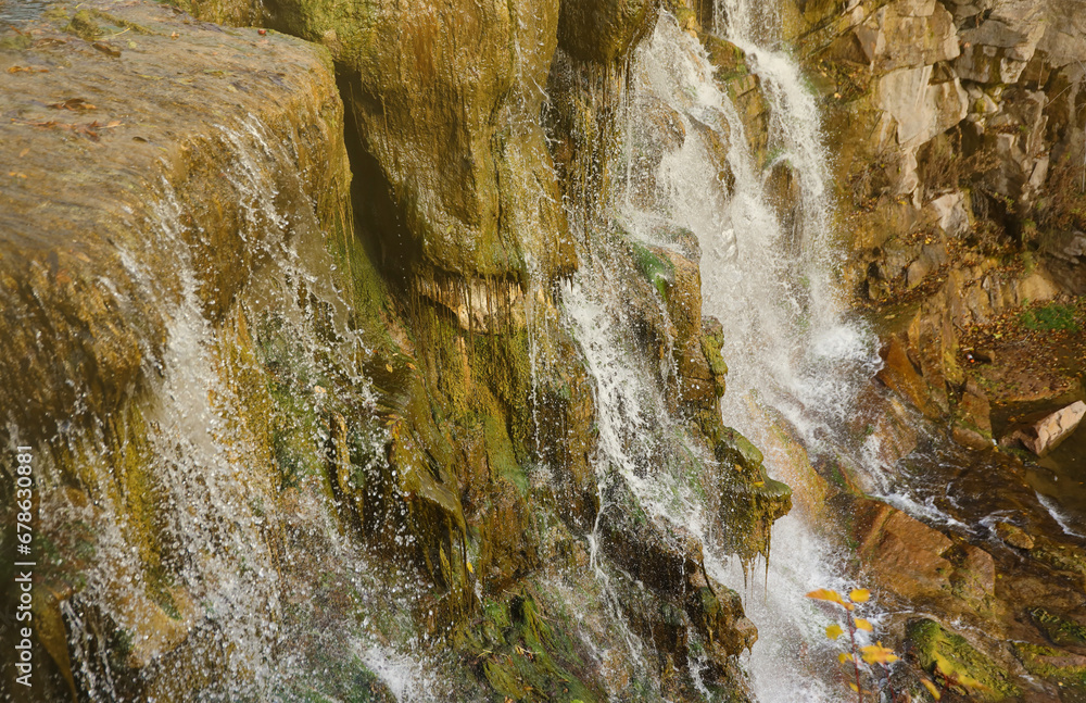 Beautiful waterfall between large rocks in the autumn forest. Sofievskiy park in Uman, Ukraine Beautiful waterfall between large rocks in the autumn forest. Sofievskiy park in Uman, Ukraine