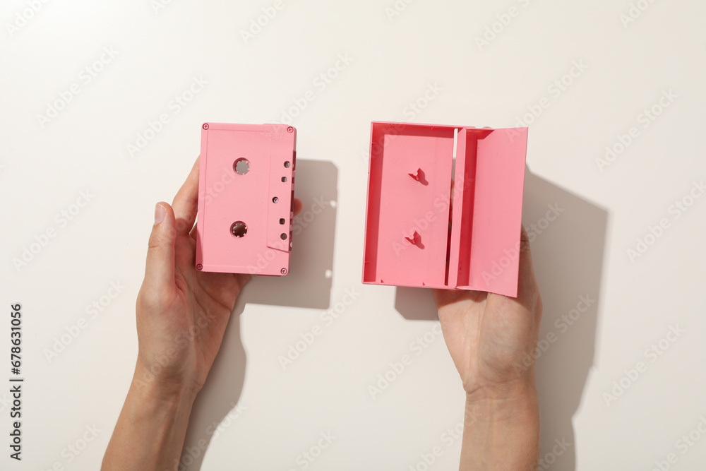 Pink cassette with and case in hands on white background, top view Pink cassette with and case in hands on white background, top view