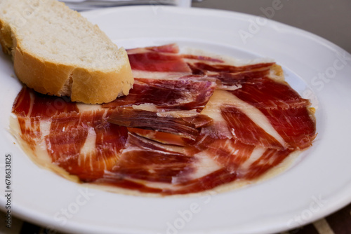 Tasty Iberico bellota ham plate with a slice of bread in a bar
