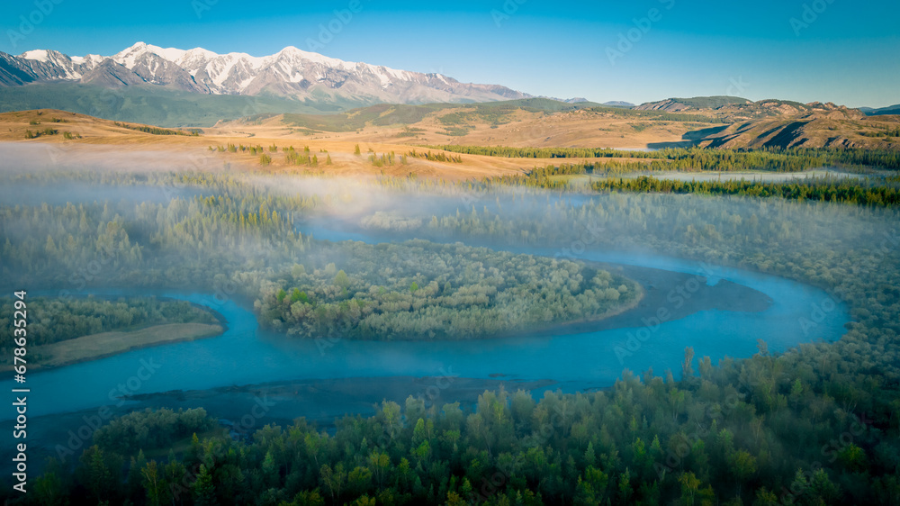 Early morning just after sunrise. Fog in the valley of the Chuya River. Coniferous forest in the fog. Kurai steppe. Summer landscape in Altai mountains, Siberia, Russia. Early morning just after sunrise. Fog in the valley of the Chuya River. Coniferous forest in the fog. Kurai steppe. Summer landscape in Altai mountains, Siberia, Russia.