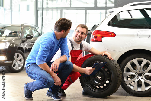 customer service in the garage - mechanic discusses repair and tyre change with one man