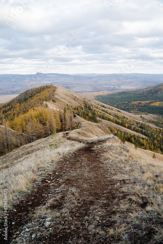 Mountain road on top of hill, hiking trail on mountain, autumn landscape, trekking in the mountains, hilly terrain.