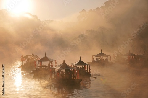 A bird's-eye view of people riding traditional Chinese boats in the morning mist at Ban Rak Thai