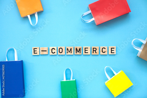 E-commerce and online shopping concept. Colourful bags and  wooden letters on the blue background. Top view.