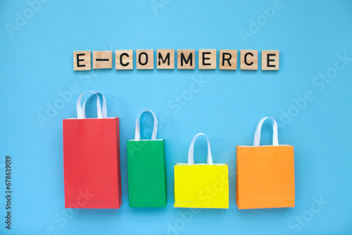 E-commerce and online shopping concept. Colourful bags and  wooden letters on the blue background. Top view.