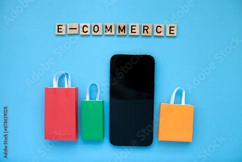 E-commerce and online shopping concept. Colourful bags and mobile phone on the blue background. Top view.