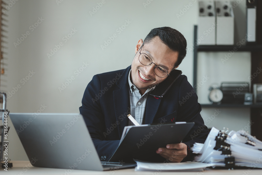Businessman is sitting and working in the office, Employee is looking for information on laptop, An entrepreneur is talking on the phone with a company customer, startup. Businessman is sitting and working in the office, Employee is looking for information on laptop, An entrepreneur is talking on the phone with a company customer, startup.