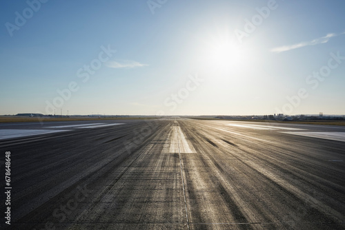 Surface level of long airport runway with directional marking against clear sky. .