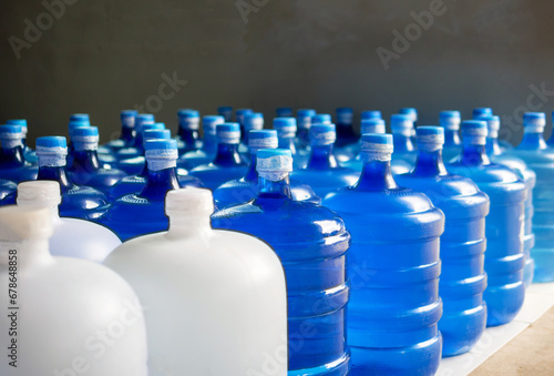 plastic big bottles or white and blue gallons of purified drinking water inside the production line. Water drink factory