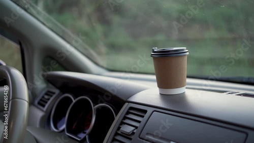 Male hand taking paper coffee cup from dashboard. Takeaway drink. Busy man with a cup of coffee in the car photo