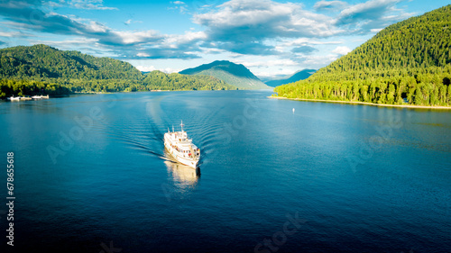 Summer Siberian landscape. Lake Teletskoye in Altai near Artybash. Boat with tourists. Mountains and forest around photo