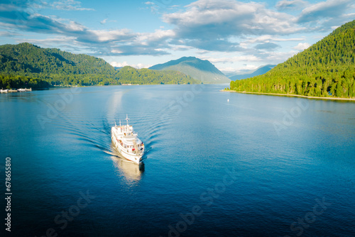 Summer Siberian landscape. Lake Teletskoye in Altai near Artybash. Boat with tourists. Mountains and forest around photo