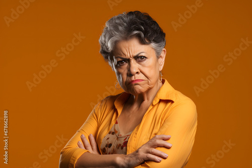 skeptic scowl senior Latin American woman, head and shoulders portrait on orange background. Neural network generated photorealistic image photo