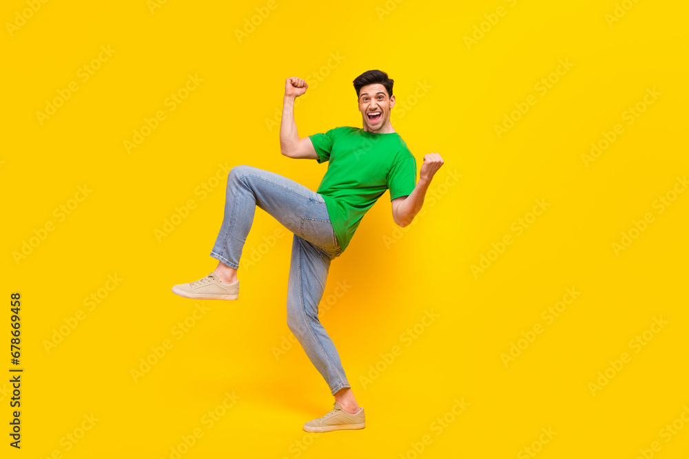 Full size photo of overjoyed guy wear stylish t-shirt clenching fists shooting yes win lottery isolated on yellow color background