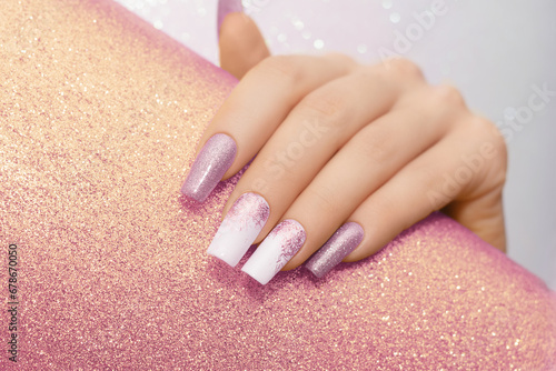 Female hand with long nails with glitter nail polish. Long pink nail design. Women hand with sparkle manicure on glitter background photo