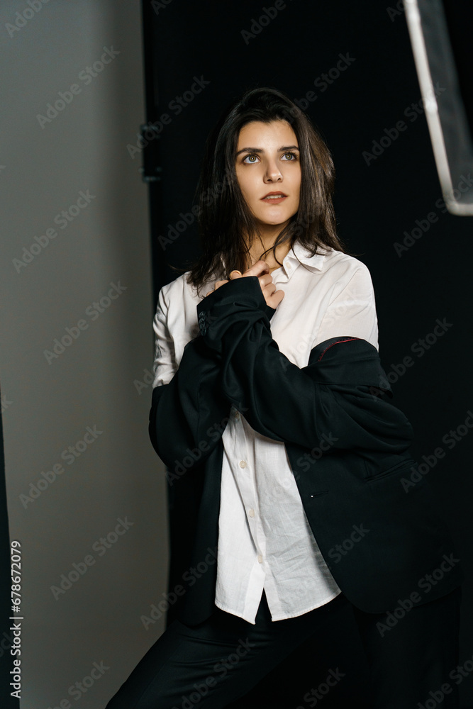 Stylish girl posing in a black suit and white shirt in a professional photo studio. Fashion shooting concept Stylish girl posing in a black suit and white shirt in a professional photo studio. Fashion shooting concept