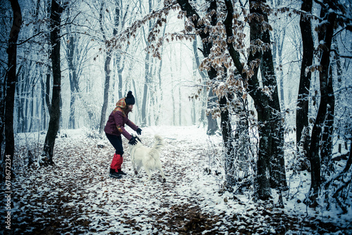 woman with dog walking in frost covered forest in winte #678672234