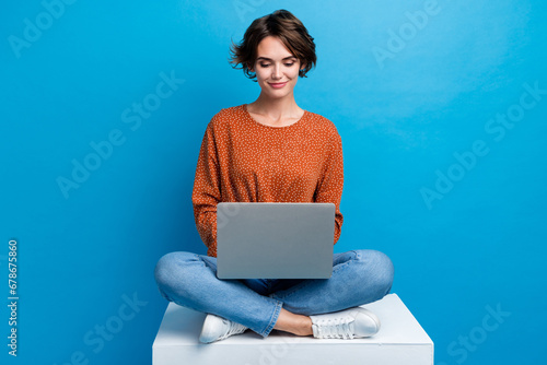 Full length photo of lovely young lady sit cube working remotely dressed stylish brown garment isolated on blue color background