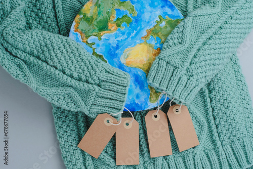 Sleeves of knitwear sweater hug the planet with tags. Responsible consumption clothes. Environmental friendliness and sustainable fashion. photo