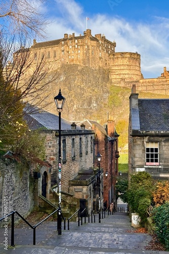 Iconic view through historic granite alley with stair towards castle in Edinburg