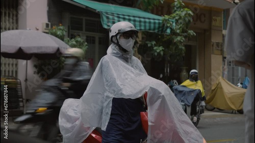 woman ready for her ride on the bike in rain in ho chi minh, a bustling city street filled with people going about their day