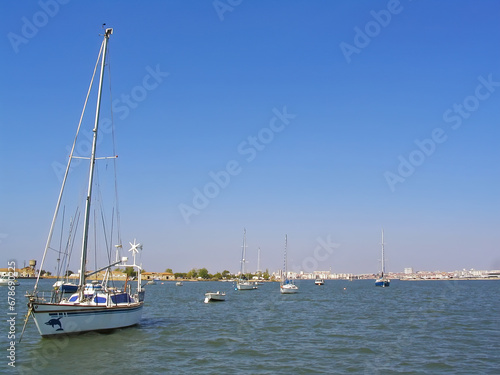 Small boats anchored on Seixal Bay with a view of the city of Barreiro on the horizon. Seixal, Setubal, Portugal photo