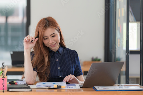 Asian woman working on a laptop computer, Working in the office with laptop concept, Young Asian woman starting a business using a laptop computer.