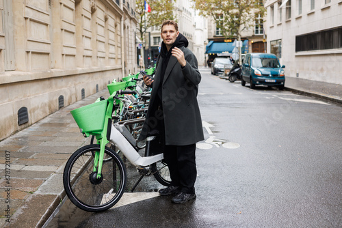 Wallpaper Mural Young man unlocks bicycle with his mobile phone. Electric bicycle new way city mobility. Green transportation. Sustainable climate neutral cities goals. Ecology mobility sustainability Torontodigital.ca