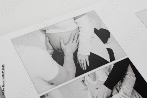 The pages of a photo book with a photo of a pregnant blonde and a man.  photo
