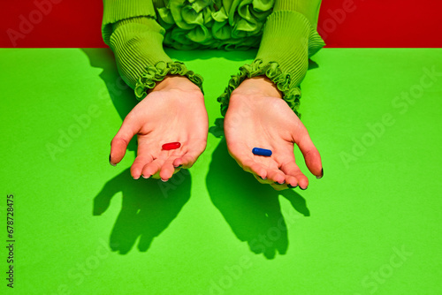 Unrecognizable woman holds two pills, red and blue tablets. Vitamins of beauty and health against sickness and ugliness. Choice true or false. Concept of medicine, viruses, immune system, healthcare. photo