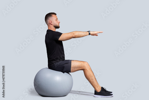 Focused muscular millennial caucasian man with beard, make exercises on fit ball for hands