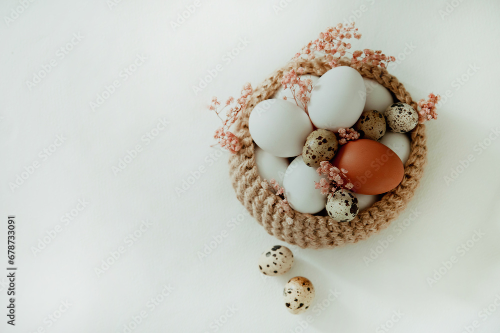 Easter white and brown eggs in a basket with flowers on a white background Easter white and brown eggs in a basket with flowers on a white background