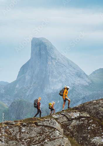 Family hiking in Norway mountains, active vacations with backpack outdoor. Parents and child traveling together healthy lifestyle adventure tour with mother, father and kid trekking in Lofoten islands photo