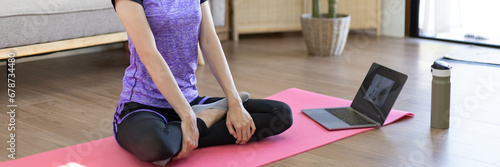 Beautiful healthy woman practicing yoga, Stretch or warm up before exercising, Calming the mind and meditating in her living room, Dumbbells and a protein shake or bottle of water, Healthy exercise.