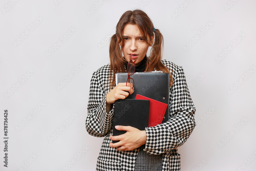 A student in glasses and a backpack holds books in her hands. A student in glasses and a backpack holds books in her hands.