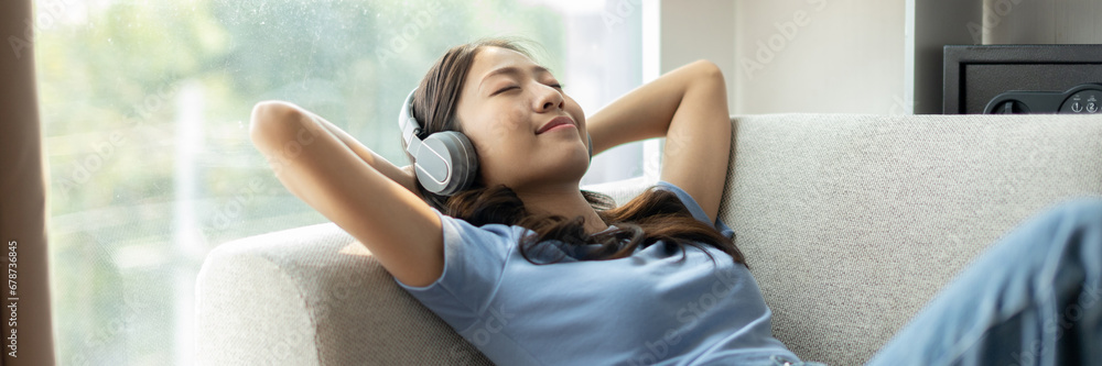 Fototapeta premium Woman happily listening to music on her favorite sofa in the living room, Relaxation time, Happy time, Feel good, Happy women resting at work after work is finished, Chill, Fatigue is eased.