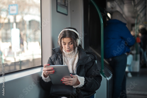 young woman listens to music on the train from a tablet.?