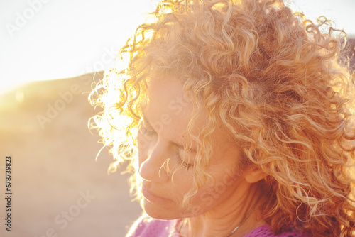 Fotografie Portrait of young adult woman with closed eyes enjoying the sunlight in sunset outdoor